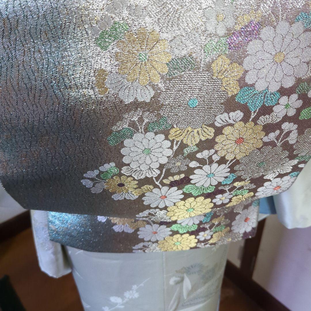 虹色に煌めくシルバーの地に、菊の花が艶やかに咲く、美しい正絹袋帯です