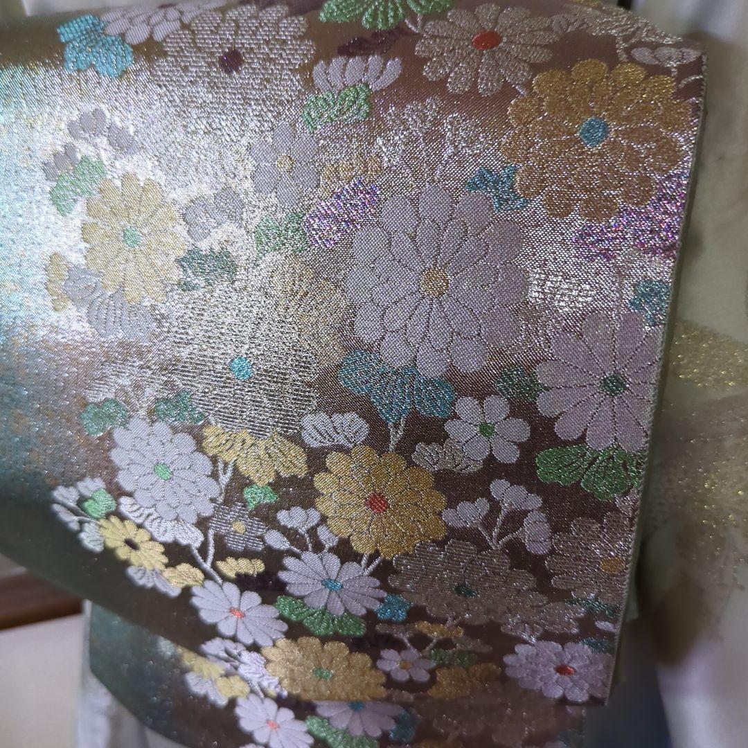 虹色に煌めくシルバーの地に、菊の花が艶やかに咲く、美しい正絹袋帯です