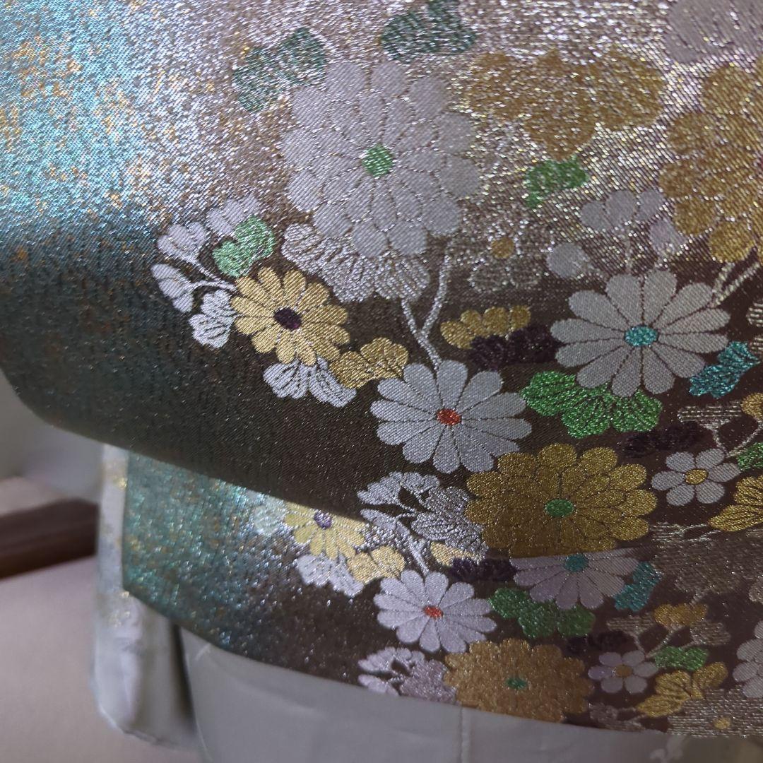 虹色に煌めくシルバーの地に、菊の花が艶やかに咲く、美しい正絹袋帯です