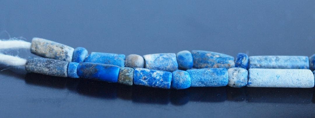 古代濃紺ラピスの管玉や丸玉をほぼ左右対称に編み、トップに斧型や多面体、80個の連