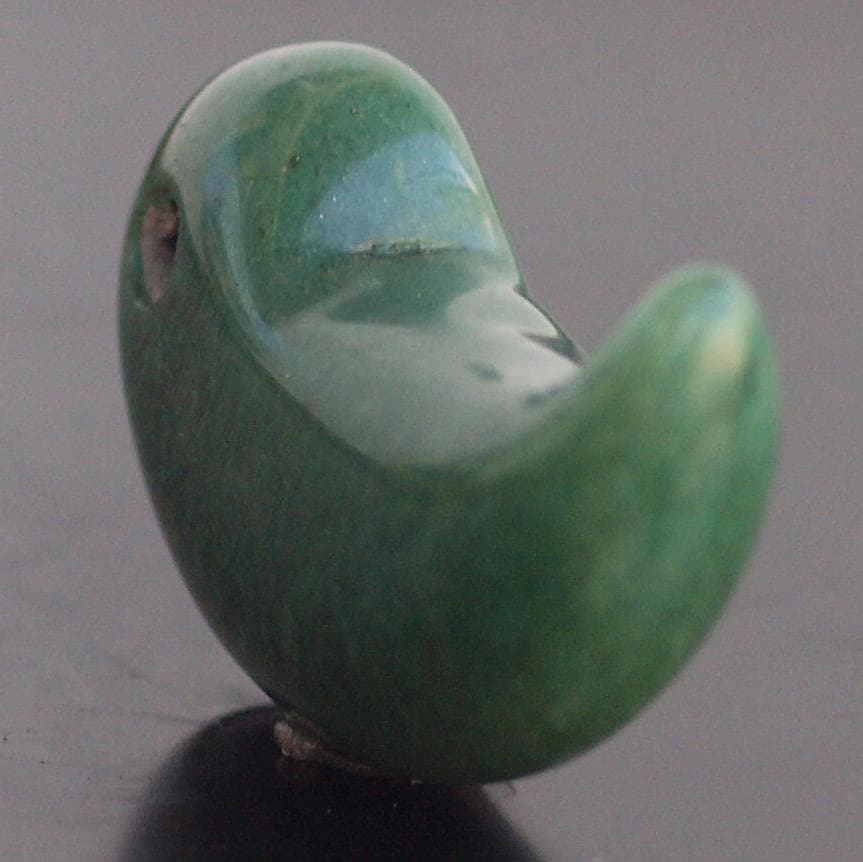 光にかざすと薄緑の細い帯状紋が出現、頭・胴の間には沈線、ずんぐり形の勾玉　沖縄の